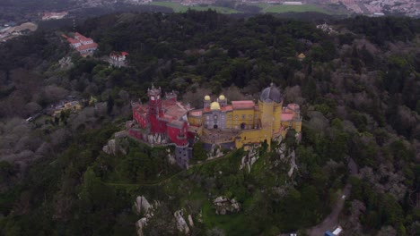 Wide-shot-of-the-incredible-Palácio-da-Pena-in-Sintra-during-cloudy-day,-aerial