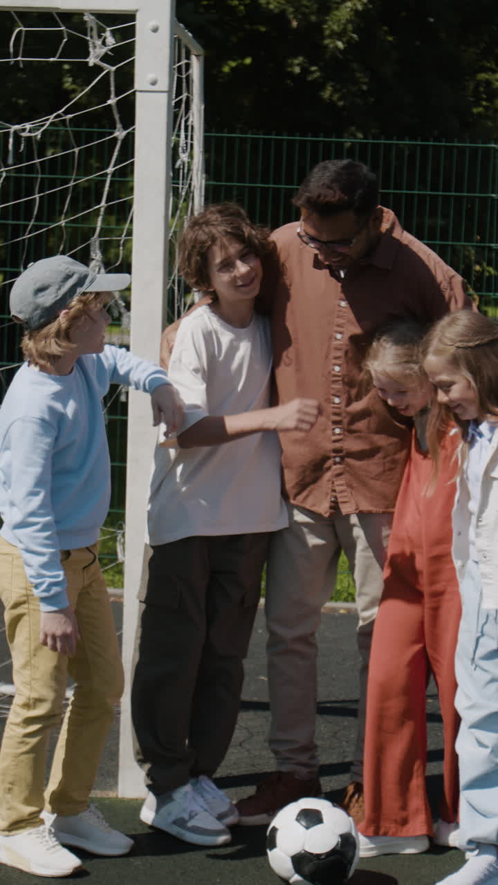 Coach and diverse children gathered by a soccer goal on an outdoor field