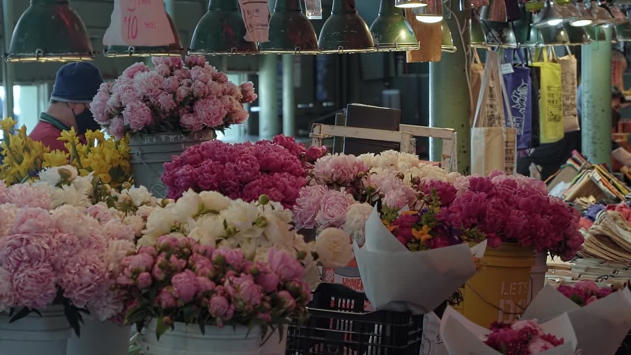Slow motion shot of a beautiful flower stall inside of the famous tourist attraction of Pike Place Market where tourists and locals come to buy flowers in Seattle, Washington USA
