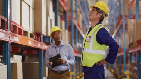 diverse male workers wearing helmet and touching back in warehouse