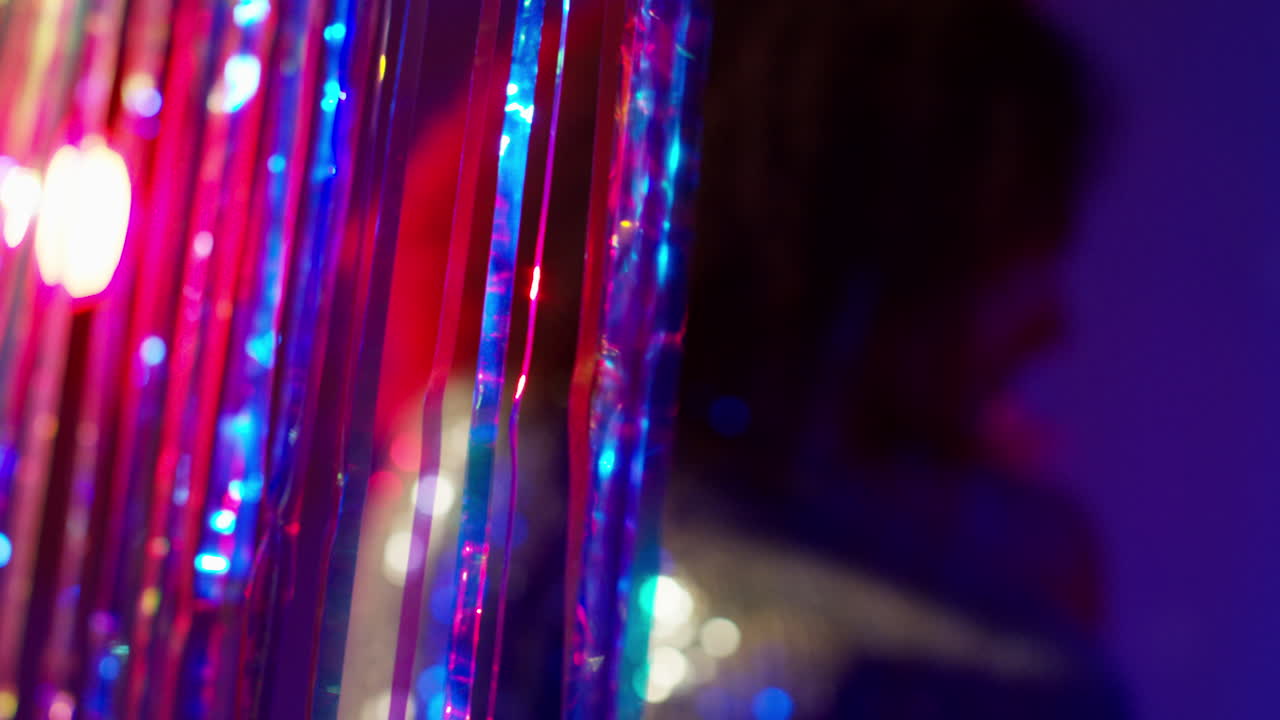 Tinsel Curtain In Night Club Or Disco With Reflected Sparkling Lights And Defocused Woman Dancing In Background