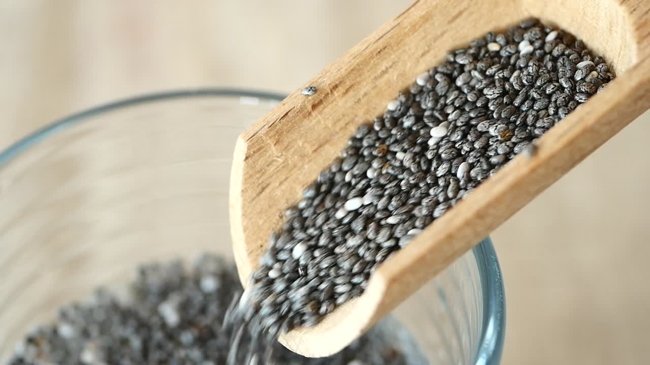 Chia Seeds in a Wooden Spoon Pouring into a Glass