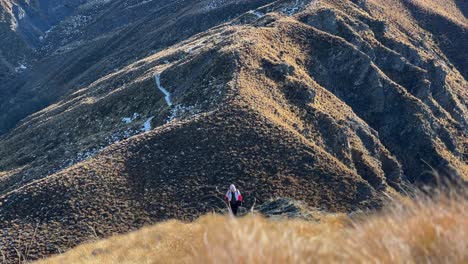 Female-hiker-approaching-on-steep-uphill-ascent-in-dry,-rugged-highlands