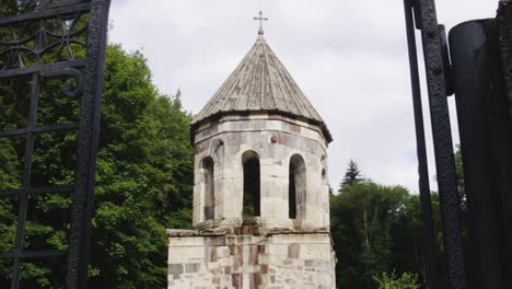 Stone-Mtsvane-monastery-bell-tower-behind-open-iron-railing-door