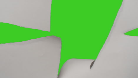 close up of hand tearing off strip of paper uncovering green screen background below 1