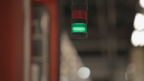 close-up of a red and green signal light in a blurry train station background