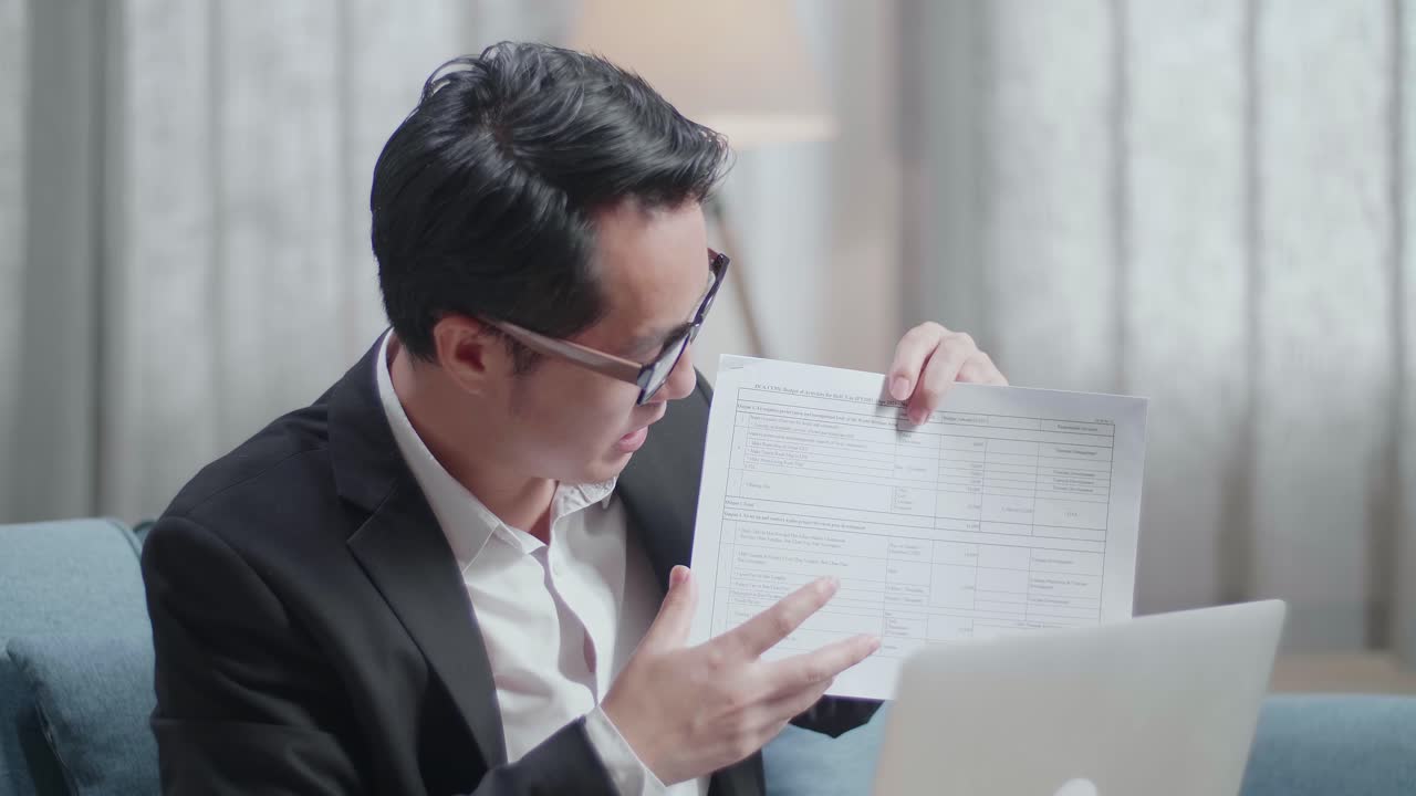 자켓과 쇼트 입은 아시아 사업가가 집에서 노트북에서 작업 종이를 제시하는 클로즈업