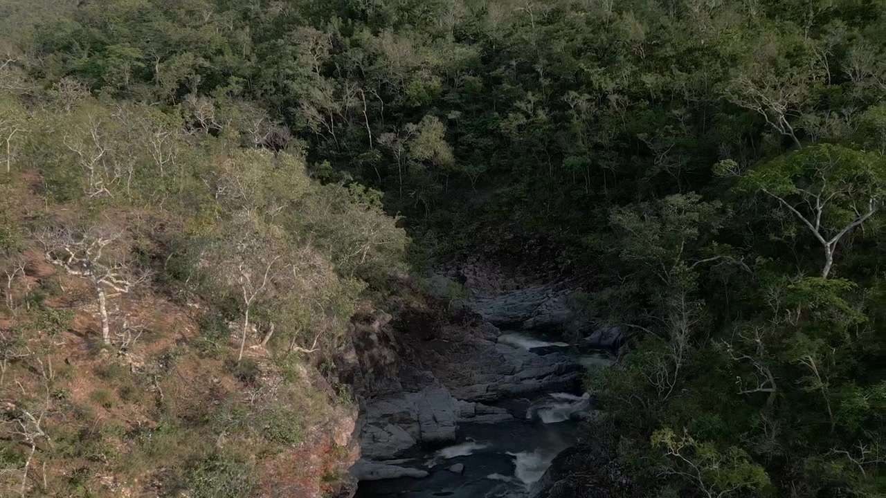 Rio São Miguel fluindo por cânion de quartzito na Serra do Segredo, Chapada dos Veadeiros, Goiás, Brasil, ladeado por mata nativa do Cerrado e formações rochosas erodidas, ascensão, inclinação para baixo, paralaxe