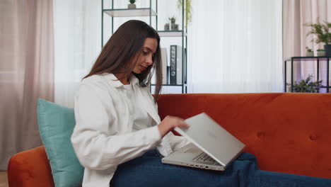 Junge-Freiberufliche-Frau,-Die-Auf-Dem-Sofa-Sitzt-Und-Den-Laptop-Schließt,-Nachdem-Sie-Die-Arbeit-Im-Wohnzimmer-Zu-Hause-Beendet-Hat