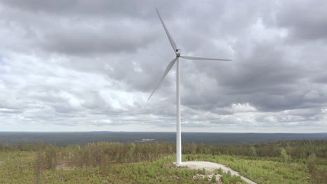 Aerial-arc-shot-of-wind-turbine-rotating-against-overcast-sky