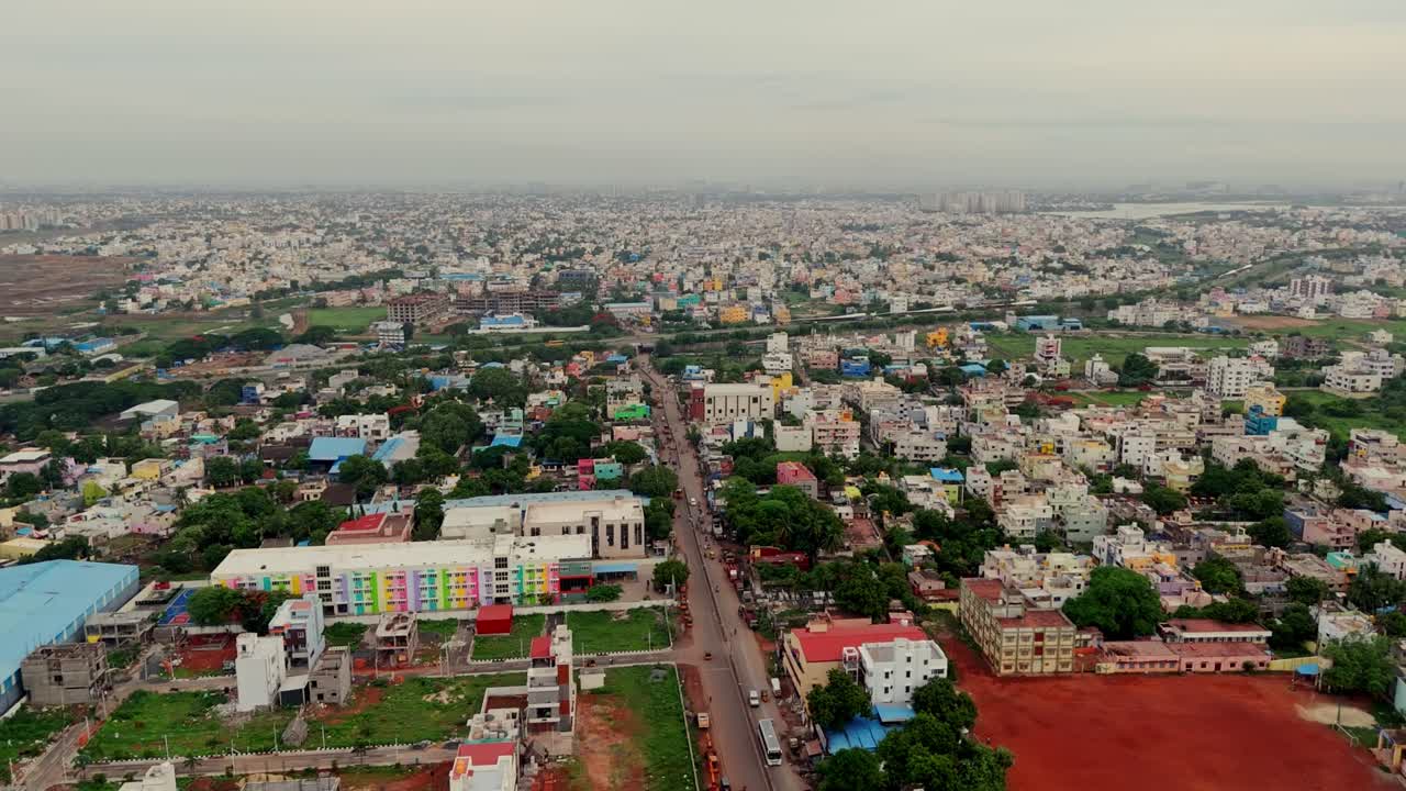Drone flying over densely populated city with busy roads in India.