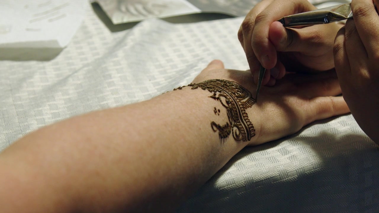 Sottili linee di macchia di mehndi sono disegnate sulla mano di una donna, opera d'arte all'henné