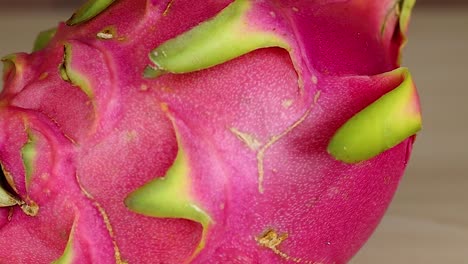 detailed view of a dragon fruit's pink and green textured surface, showcasing its unique spiky features.