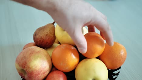 man chooses between an apple and a tangerine.