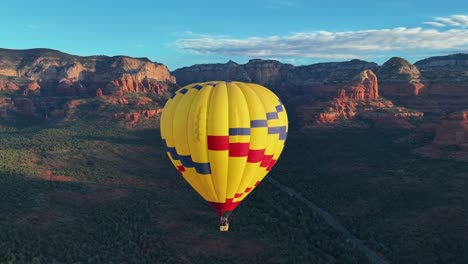 hot air balloon flying at a high altitude with mountain cliffs in background in sedona, arizona, united states