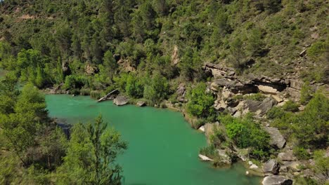 Murillo-de-Gallego-Bridge-in-Huesca-with-turquoise-river-flowing-through-lush-greenery,-aerial-view