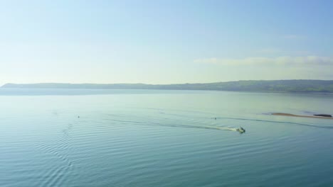 aerial flying over blue ocean on sunny day, boat cruises by