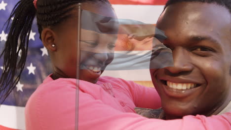 animation of flag of america waving over smiling african american father and daughter embracing
