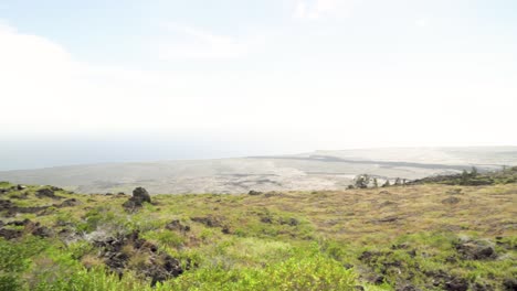 panorámica de izquierda a derecha de un campo de lava que ha sido reclamado por la hierba desde un punto de vista alto hasta el océano