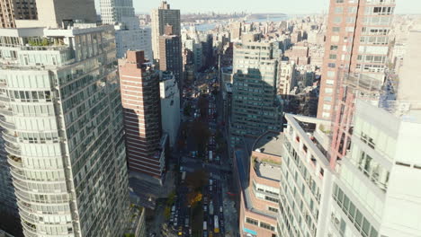 Forwards-descending-fly-above-wide-street-clogged-with-heavy-traffic.-High-rise-buildings-in-city.-Manhattan,-New-York-City,-USA
