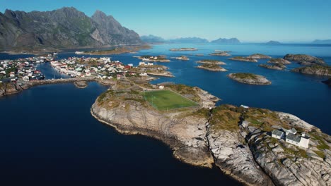 famous football field in henningsvær with dramatic mountain backdrop. lofoten norway aerial drone.