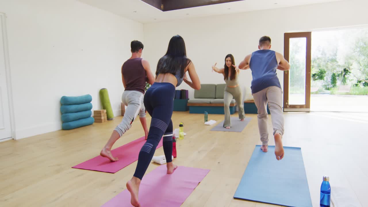 instructora caucásica que demuestra posturas de yoga a un grupo diverso en una clase de yoga