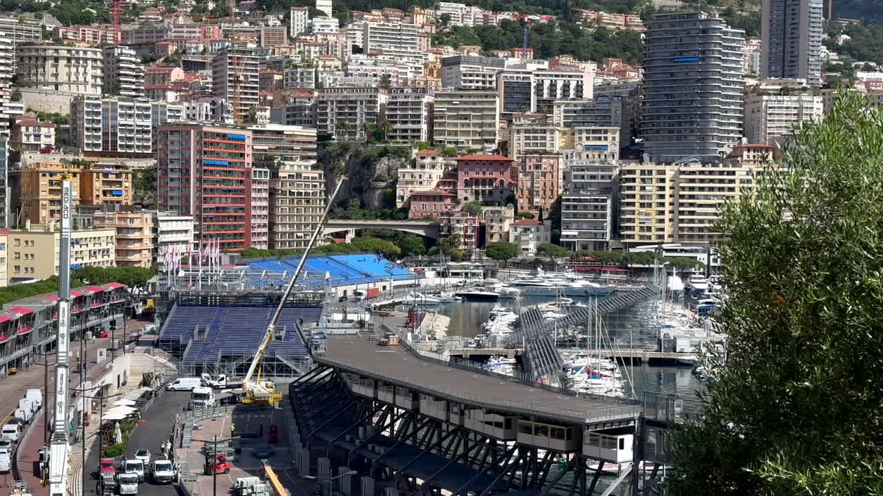 Monaco City with stands for spectators during formula 1 grand prix. Luxury downtown with tower houses on sunny day. Wide shot tilt up.