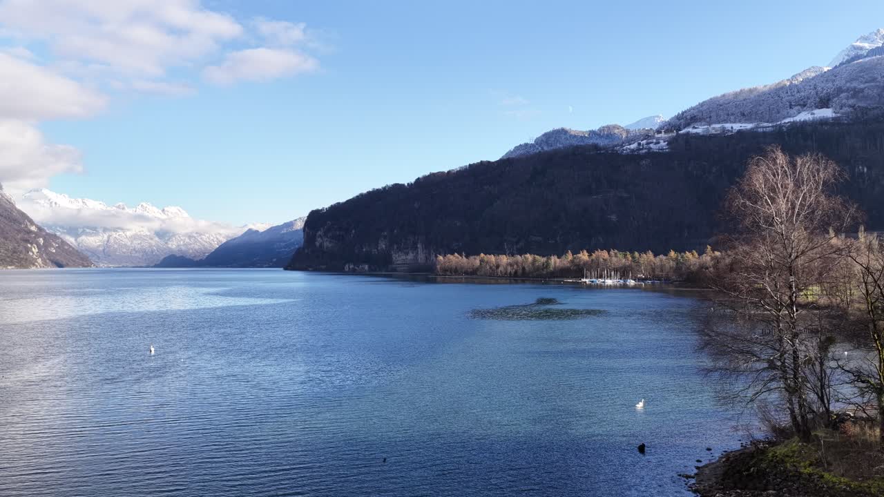 Walensee Switzerland with clear blue water and winter mountains as drone moves forward, calm alpine lake landscape