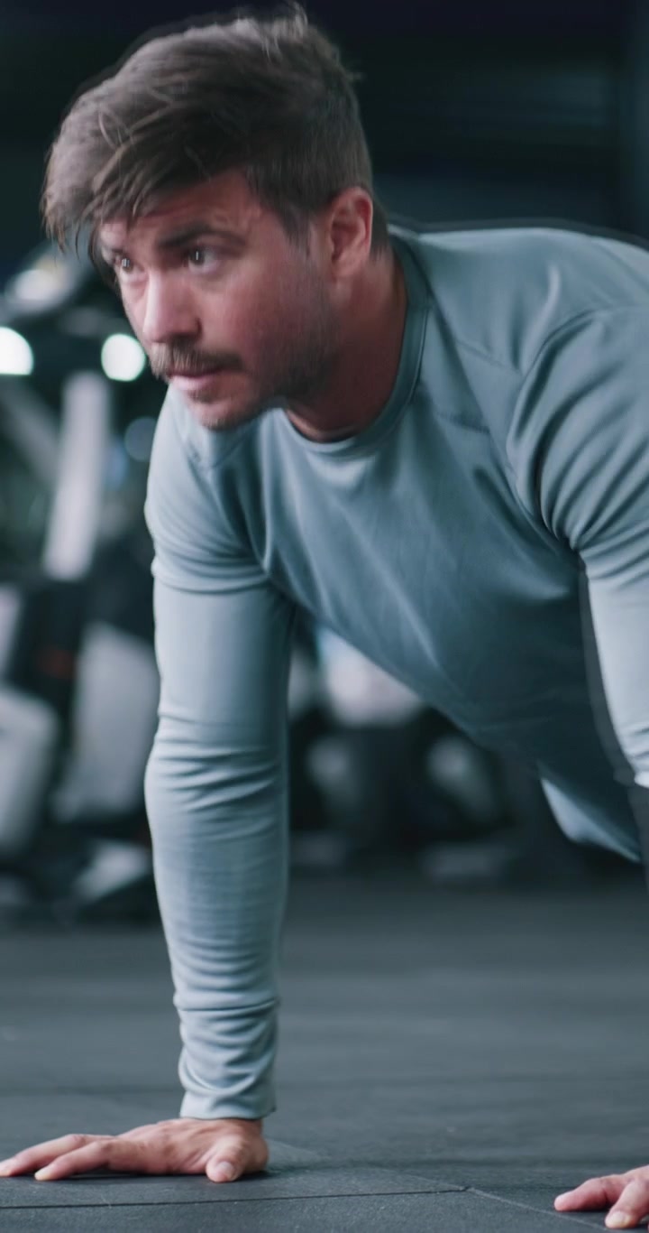 Fit Man Performing Pushups in a Modern Gym