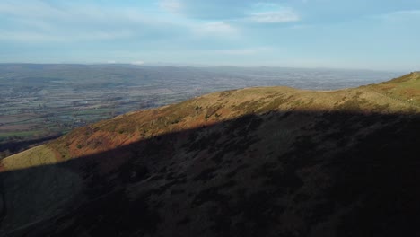 early sunlight on highland mountain peak aerial orbit left view across vast frosty idyllic farmland countryside