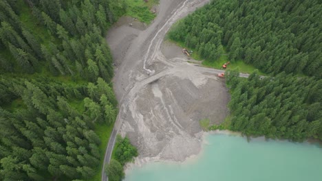 Amidst-the-verdant-alpine-trees,-the-scarred-landscape-tells-a-tale-of-a-recent-mudslide,-with-recovery-efforts-clearly-underway