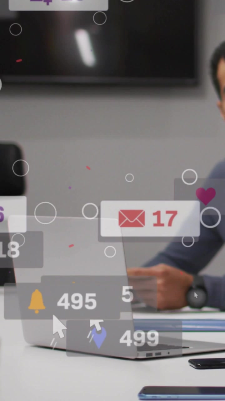 Vertical video: Man tapping phone causing likes and replies floating over laptop showing marketing
