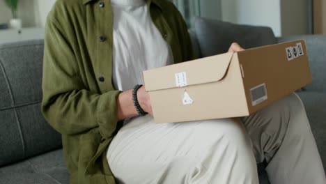 man unboxing a package on a couch