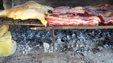 Hot-charcoal-cooking-the-meat-slowly-in-a-traditional-Asado,-Argentina