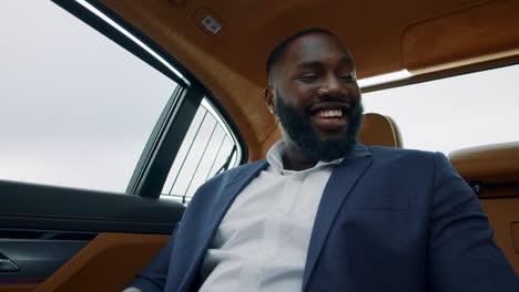 portrait of businessman looking away at car. african man showing phone at car