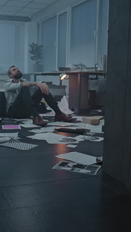 stressed man sitting on the floor in a messy office