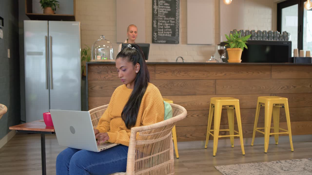 Entering cafe Indian woman typing on laptop, White barista serving espresso to African American man