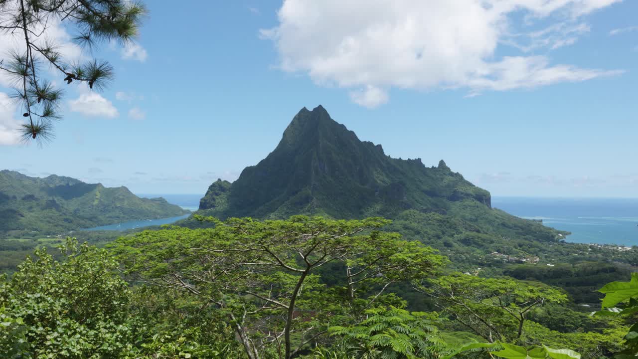 View of mountains, Mount Rotui, forest a lagoon and the ocean from a viewpoint in a tropical pacific island on a sunny day in Three Pines Lookout, Moorea, French Polynesia.