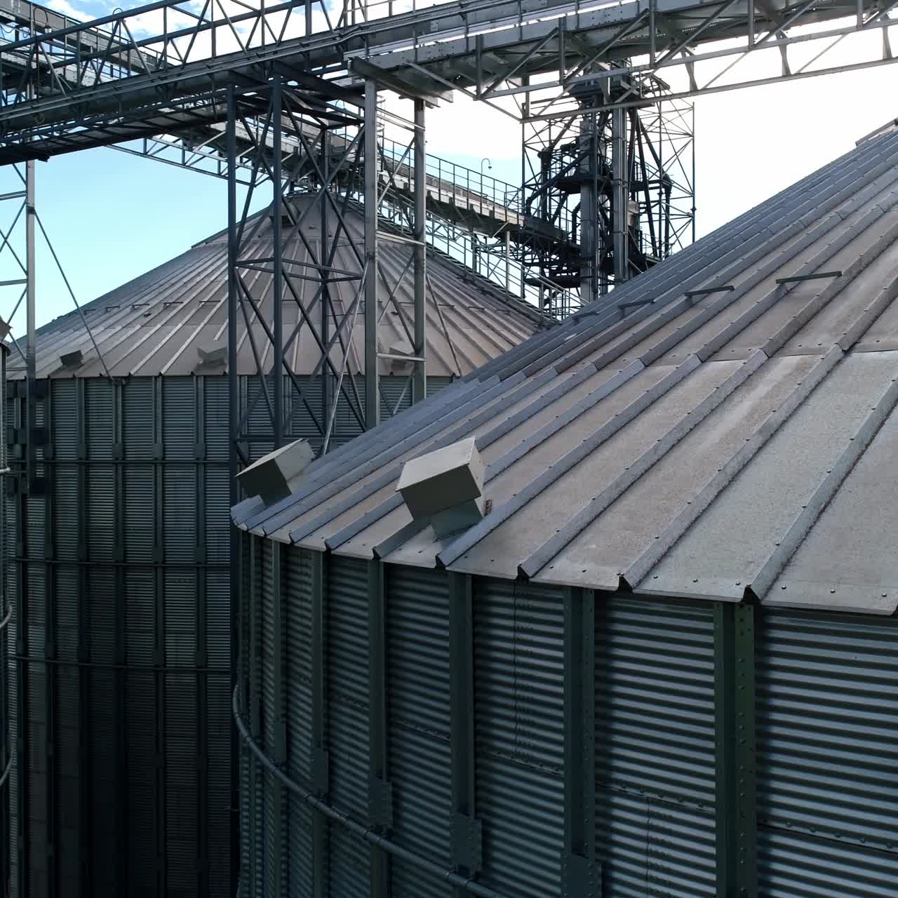 Large silver granary. Modern grain elevators. Metal industrial silos for agribusiness. New plant for storing crop. Close-up. Drone view.