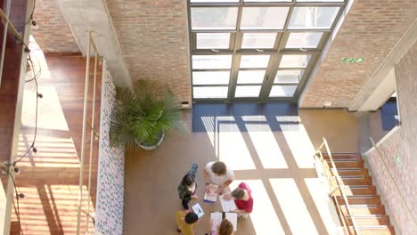 high angle of five diverse male and female colleagues in casual discussion in corridor, slow motion