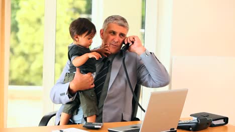 hombre haciendo trabajo de oficina mientras sostiene al bebé