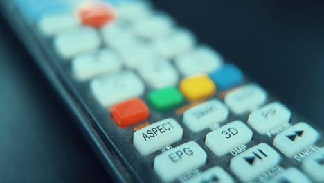 a macro close-up shot of a black tv remote with white and colorful buttons, studio lighting, slow motion, 120 fps, full hd