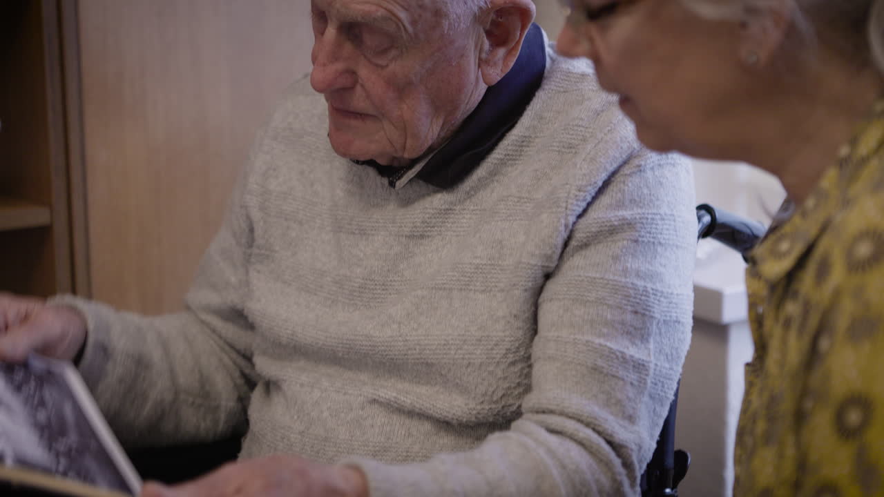 Elderly man looking at photo album in wheelchair