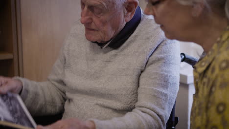 elderly man looking at photo album in wheelchair