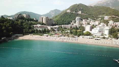 Drone-Acercándose-A-La-Ciudad-Turística-De-Playa-En-Montenegro-Mar-Adriático-Ciudad-De-Becici-Budva-Destino-De-Vacaciones-De-Viaje