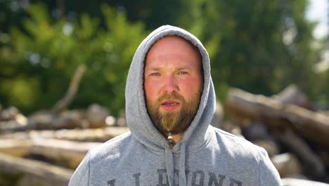 sporty man wearing hooded jacket is lifting barbell outdoor