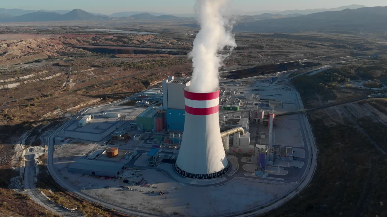 Drone, fumo e vapore da camino di una centrale elettrica a carbone, inquadratura dal basso verso l'alto al tramonto.