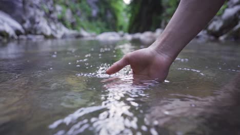 poniendo la mano en el agua limpia y clara del arroyo.