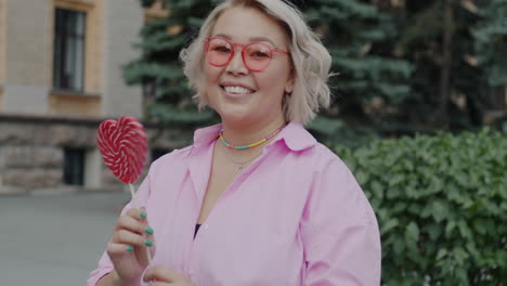 smiling woman with heart-shaped lollipop