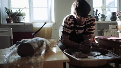 a male potter creates a beautiful relief vase on a potter's wheel.